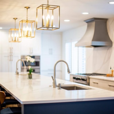 The kitchen features an island with white a marble countertop and stainless steel sink